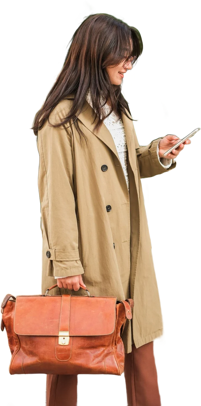Une professionnelle de la beauté en trench, mallette en cuir à la main, consulte son téléphone entre deux rendez-vous